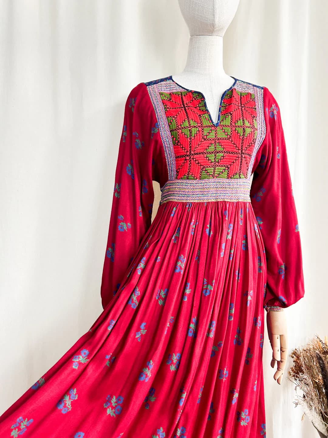 Side view of a deep burgundy embroidered Afghan dress with full sleeves.