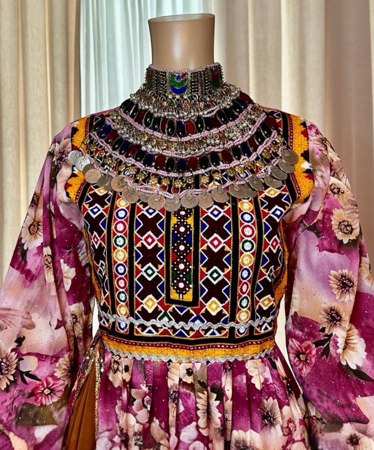 Close view of hand mirror, coin and bead work on a kuchi dress bodice.