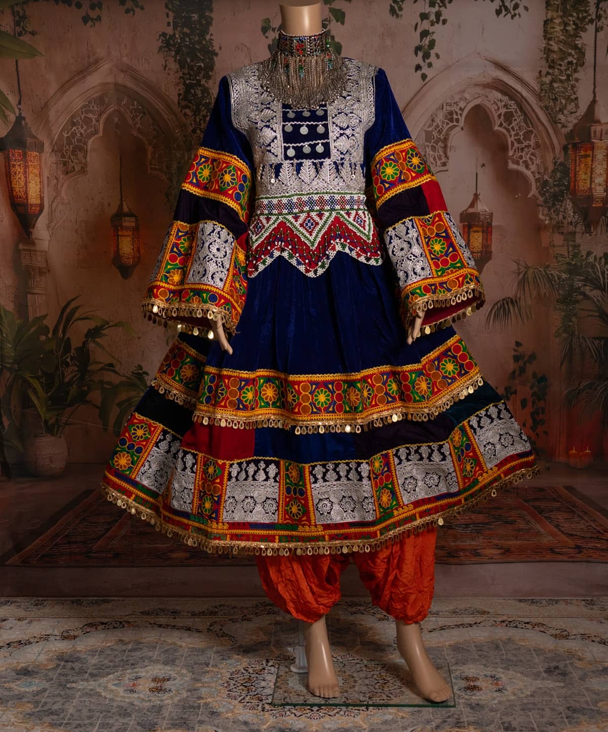 Royal purple hand-embroidered Afghan dress photographed beside a stone column.