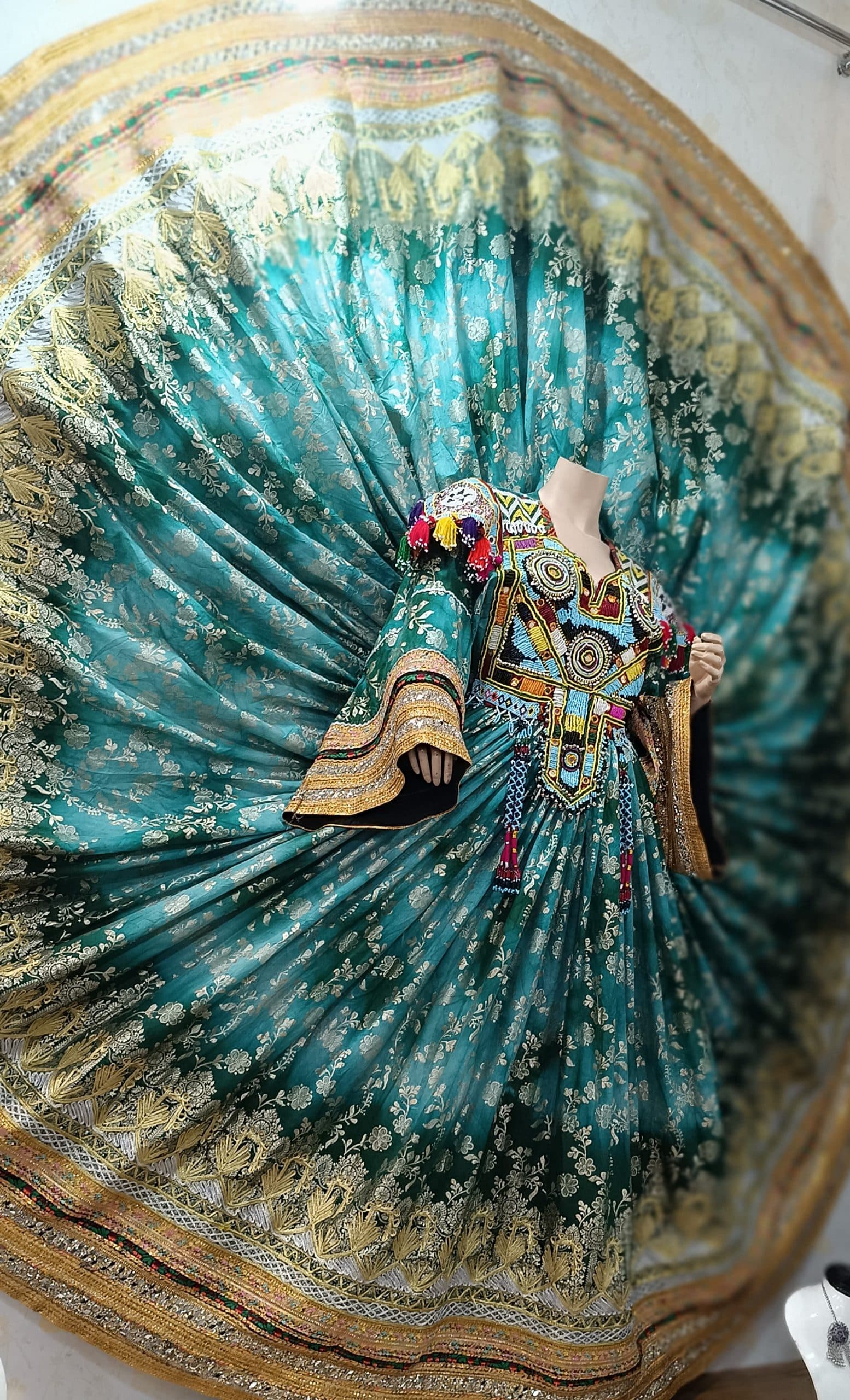 Teal and gold brocade Afghan gandi dress with a dramatic fanned skirt.